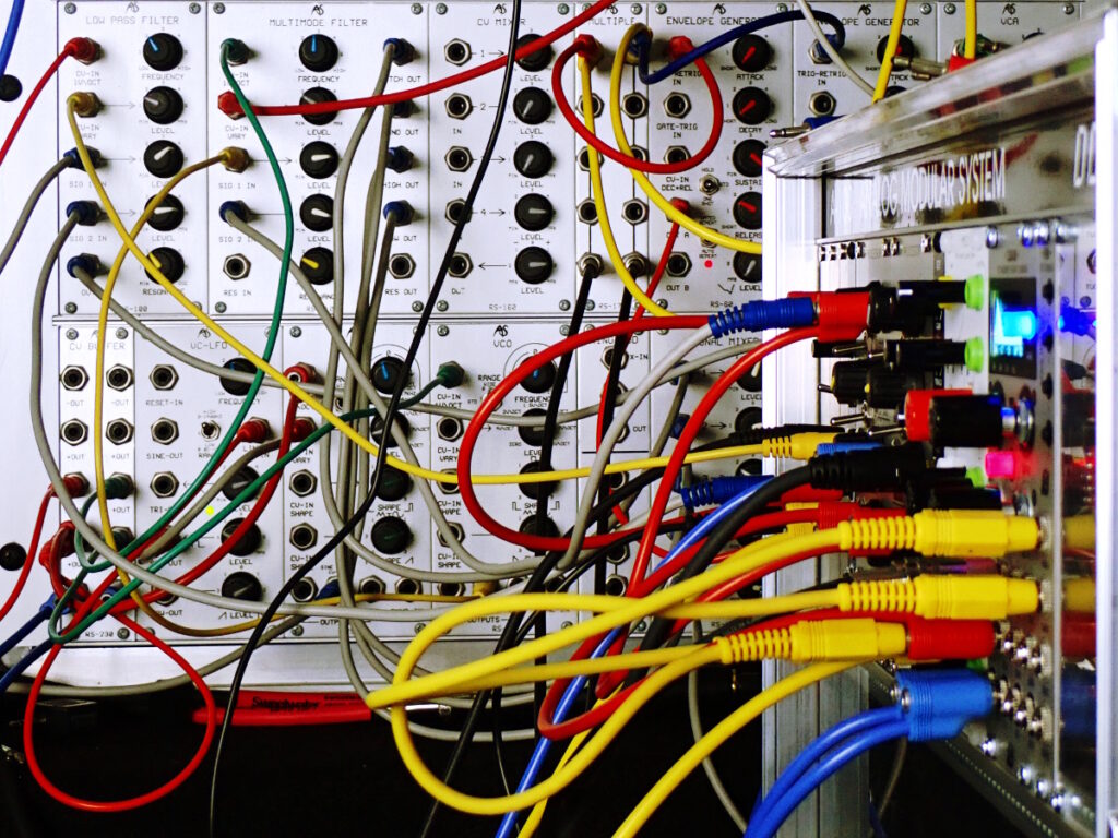 Photo of Eurorack synthesizers in a studio, and a mess of cords